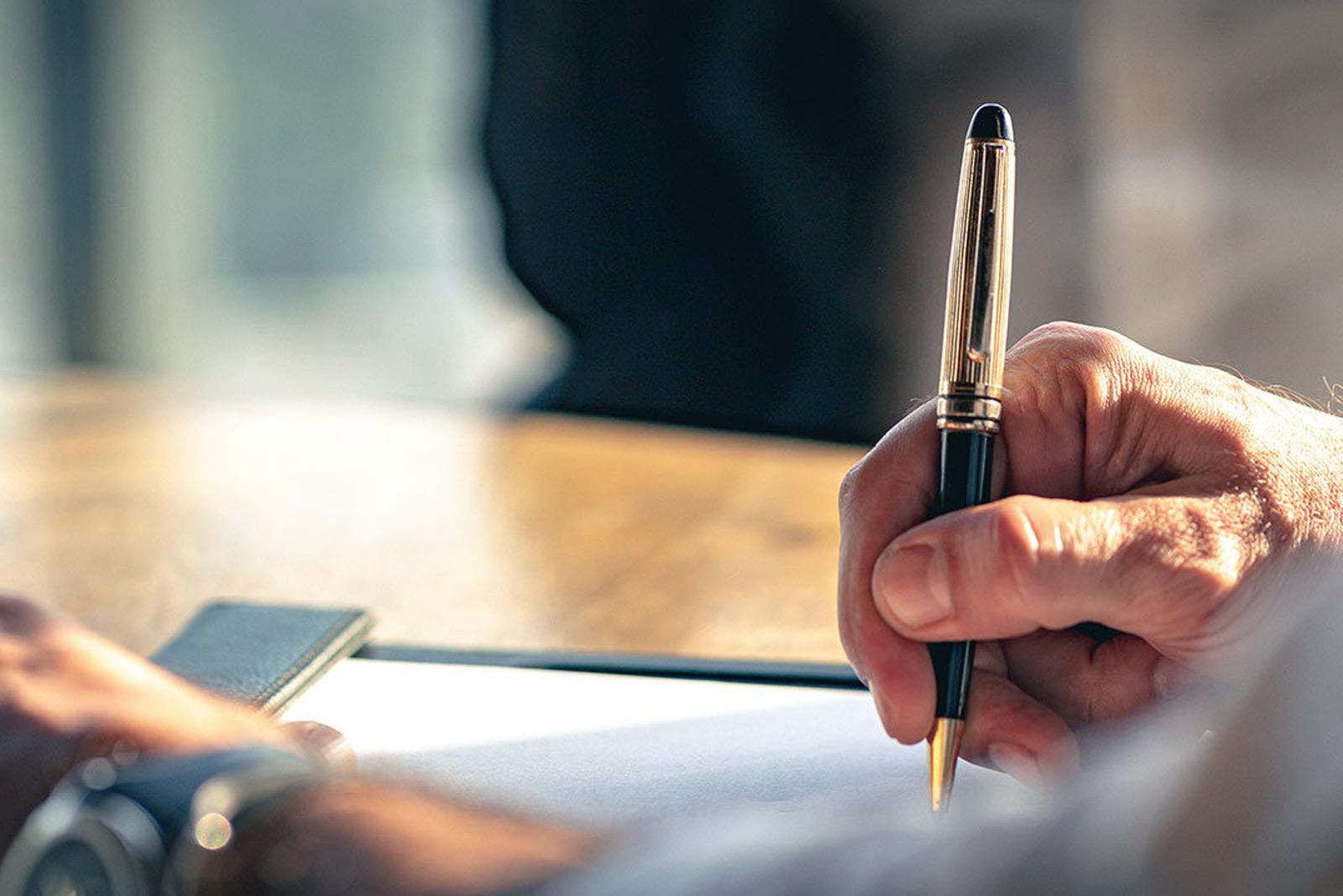 Man holding pen and writing in an agenda